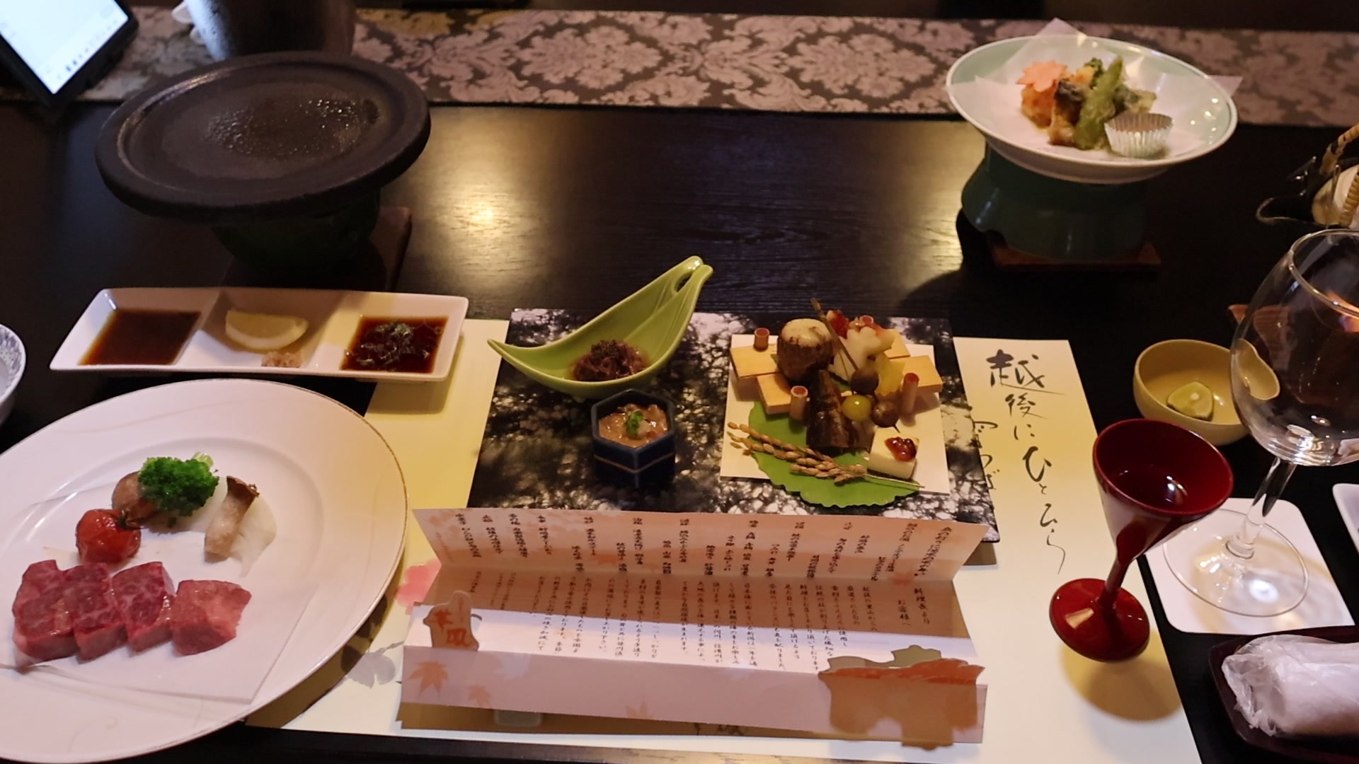 RF16mm で撮った動画から切り出した夕食の1コマ。座卓に並んだ料理とお品書きが1画面に収まっている