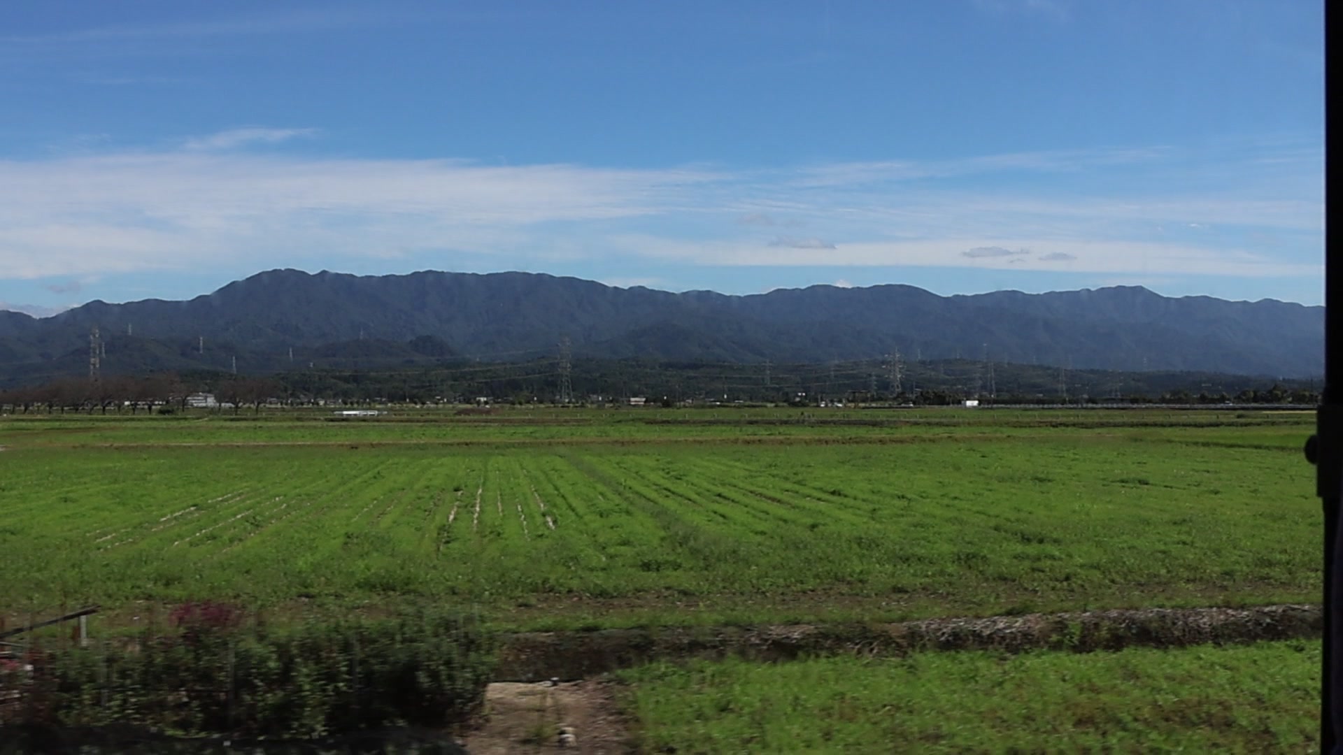 18-150mm で撮った動画から切り出した1コマ。田んぼの向こうに山並みが続く遠くの景色